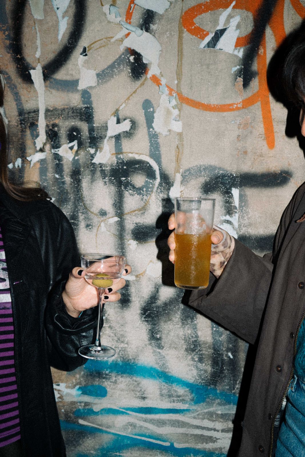 Persone con drink davanti a un muro urbano